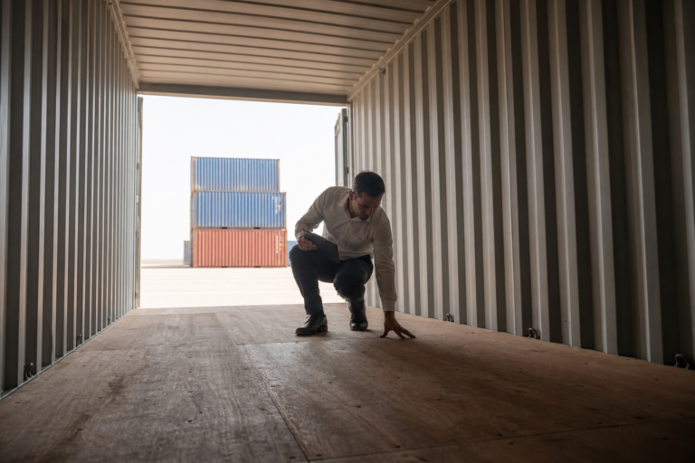 Buyer inspecting the plywood floor and steel walls inside an empty shipping container